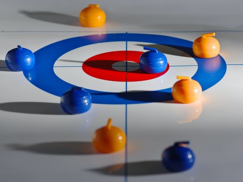 Spielsteine auf einem Curling-Spielfeld in Orange und Blau