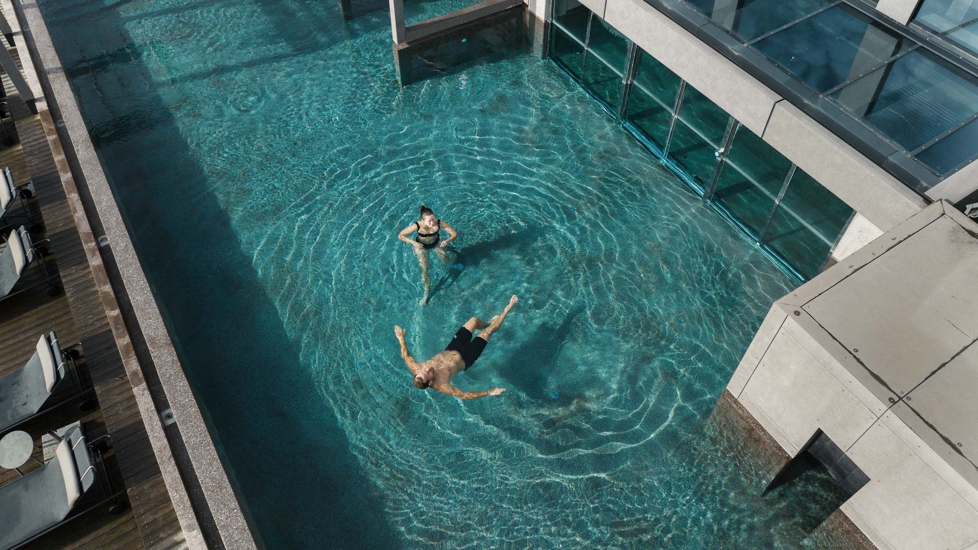 Personen entspannen im klaren Pool neben einem modernen Gebäude