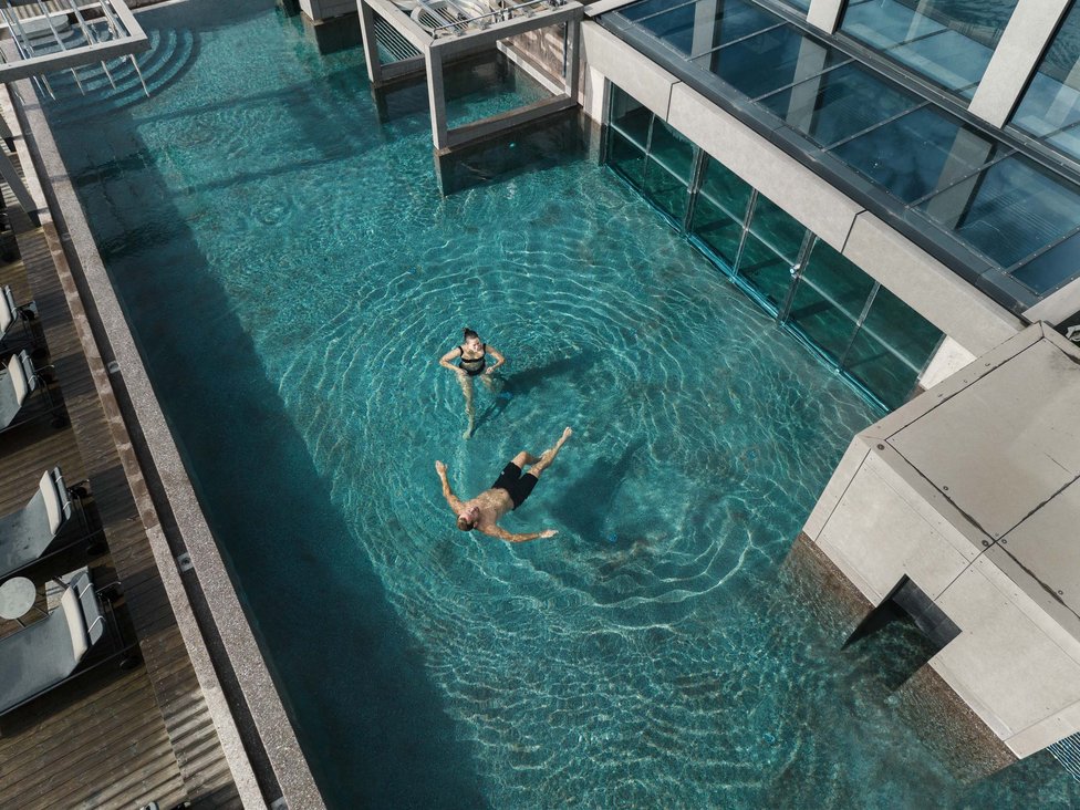 Personen entspannen im klaren Pool neben einem modernen Gebäude