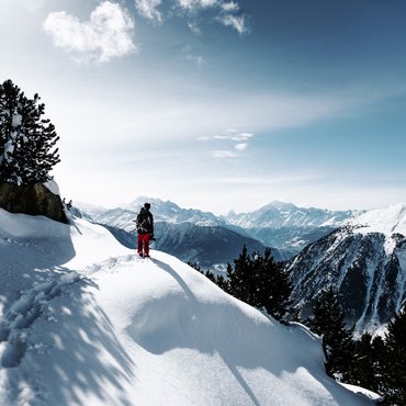 Person in roter Hose wandert durch schneebedeckte Berge bei klarem Himmel