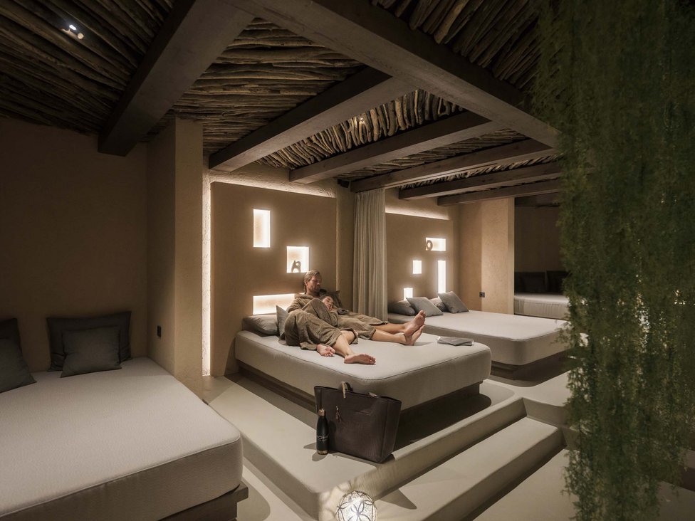 Paar entspannt auf Bett in gedämpft beleuchtetem Spa-Ruheraum