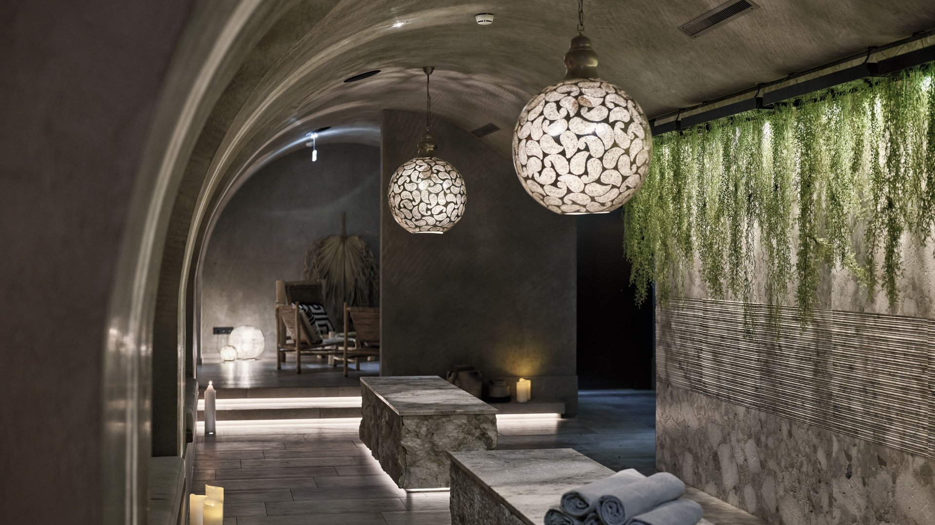 Ruhebereich mit Steinliegen, schönen Lampen und Pflanzenwand im Spa