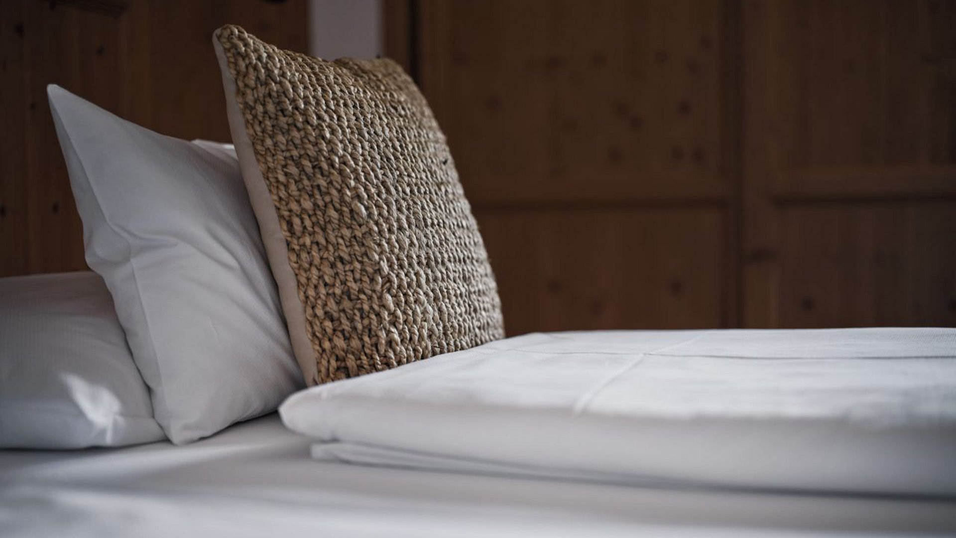 Nahaufnahme eines sauber gemachten Bettes mit weißen Laken und Kissen