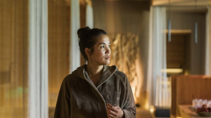 Wellness und Luxus: Ihr Hotel in Tirol Frau im braunen Bademantel schaut nachdenklich in einem warm beleuchteten Raum