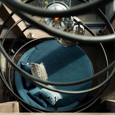 Blick von oben auf runden blauen Sessel mit Kissen und Leuchte im modernen Raum