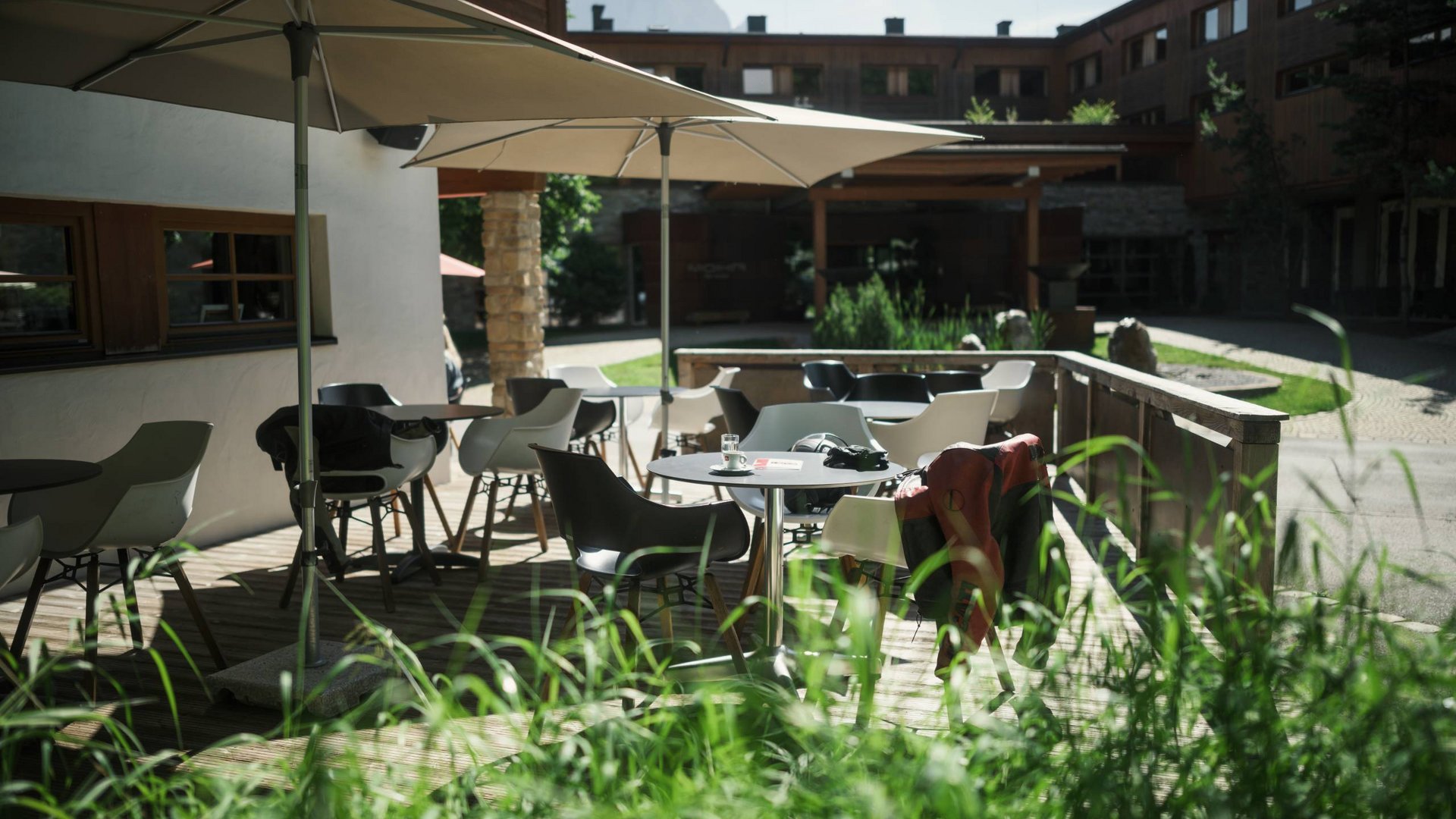 Sitzbereich im Freien mit Tischen, Stühlen und Sonnenschirmen vor einem Gebäude