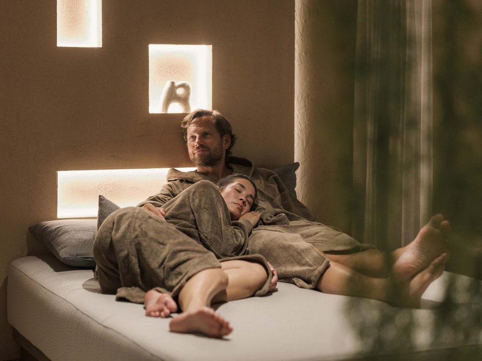 Paar entspannt im Spa-Bereich auf einer Liege in Bademänteln