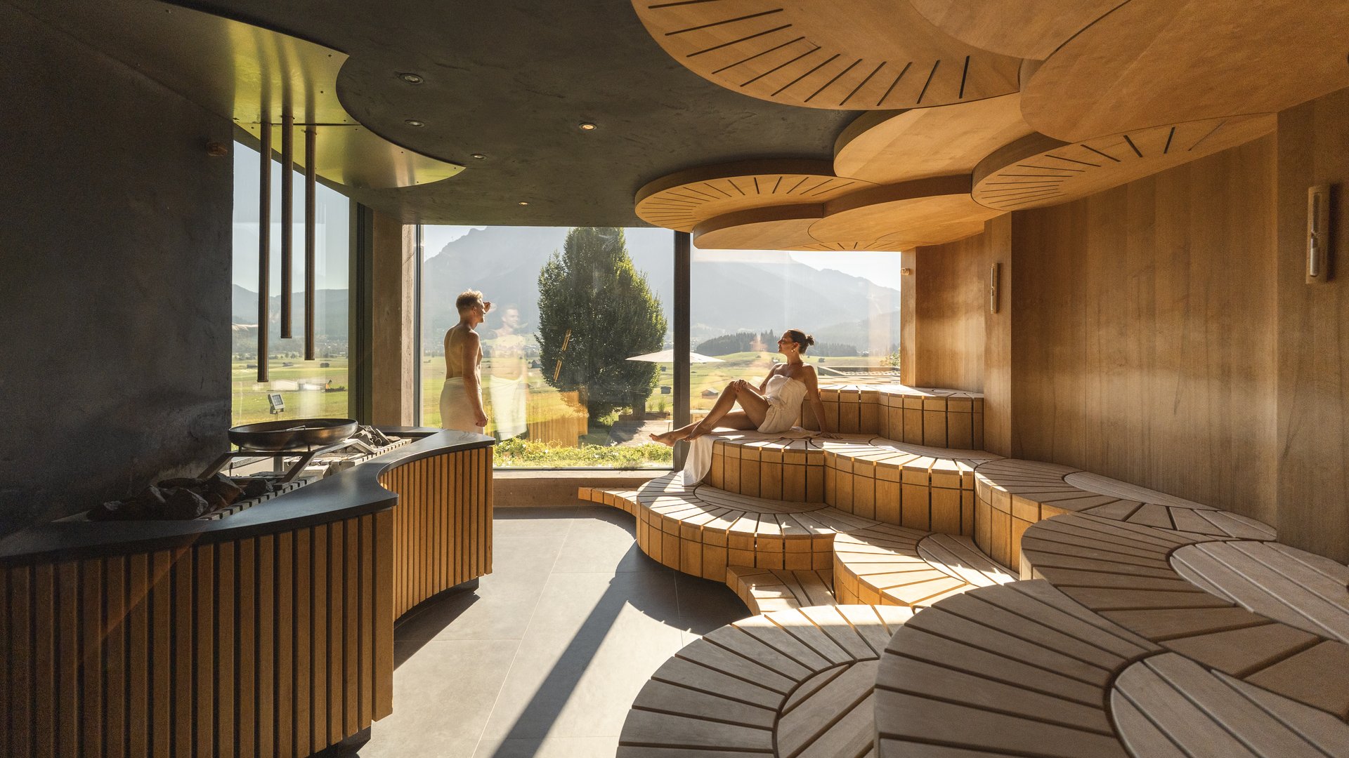 Großzügig und exklusiv: Ihr Wellnessurlaub in Tirol Ruheraum mit Holzliegen und Bergblick durch große Fenster