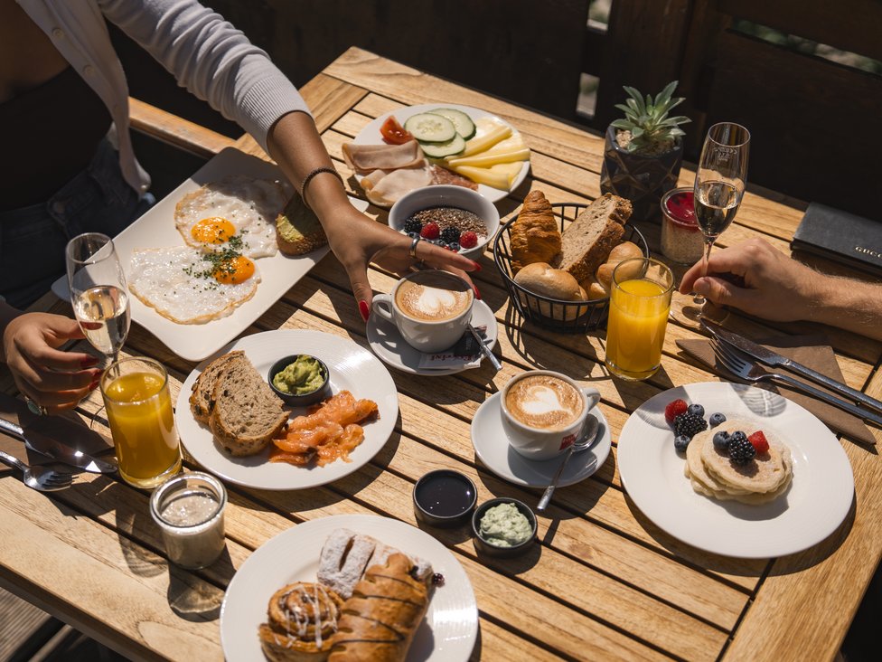 Frühstückstisch mit Eiern, Lachs, Gebäck, Obst, Kaffee und Orangensaft