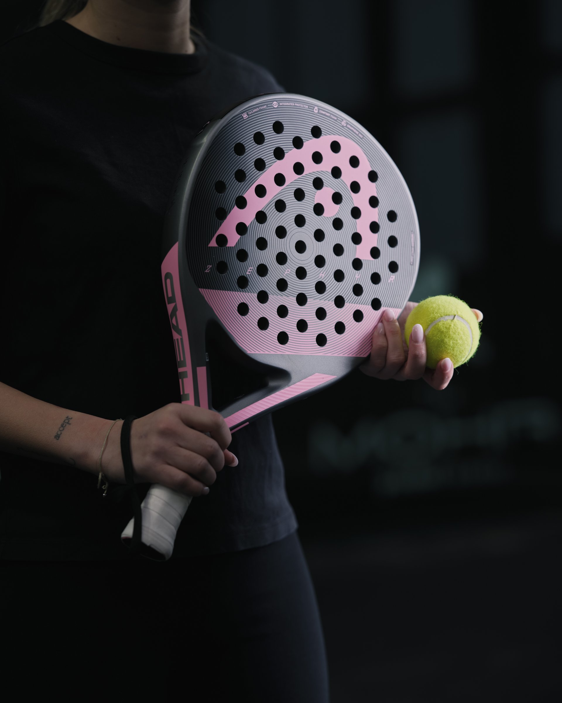 Person mit rosafarbenem Padel-Schläger und gelbem Ball