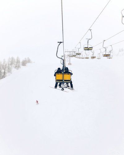 Wellness und Luxus: Ihr Hotel in Tirol Zwei Personen auf einem Sessellift im verschneiten Skigebiet