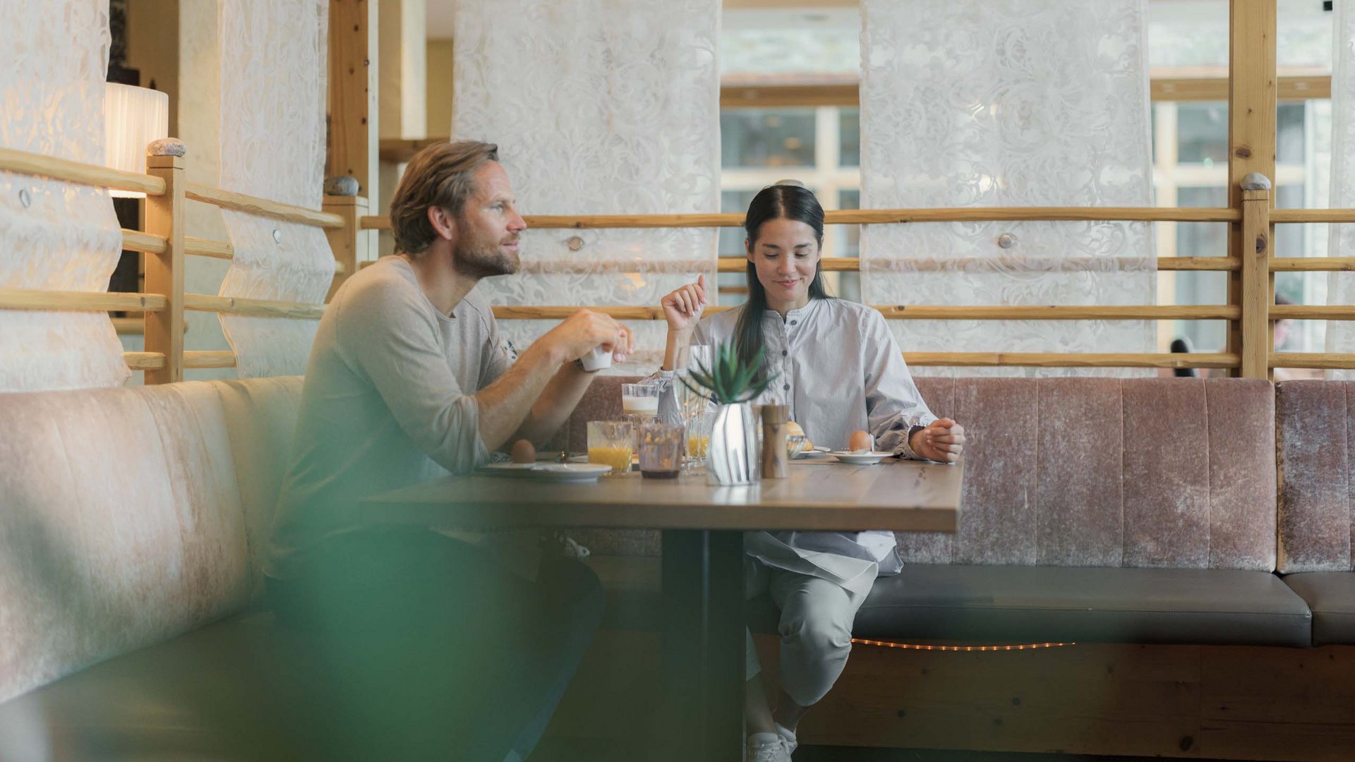 Paar frühstückt gemütlich an einem Holztisch in einem Café