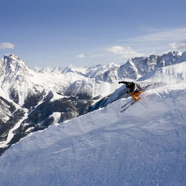 Skifahrer springt im Pulverschnee vor verschneiten Bergen