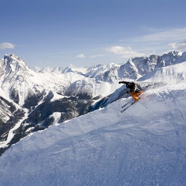 Skifahrer springt im Pulverschnee vor verschneiten Bergen