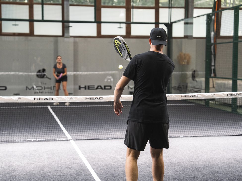 Zwei Personen spielen Padel-Tennis auf einem Indoor-Platz