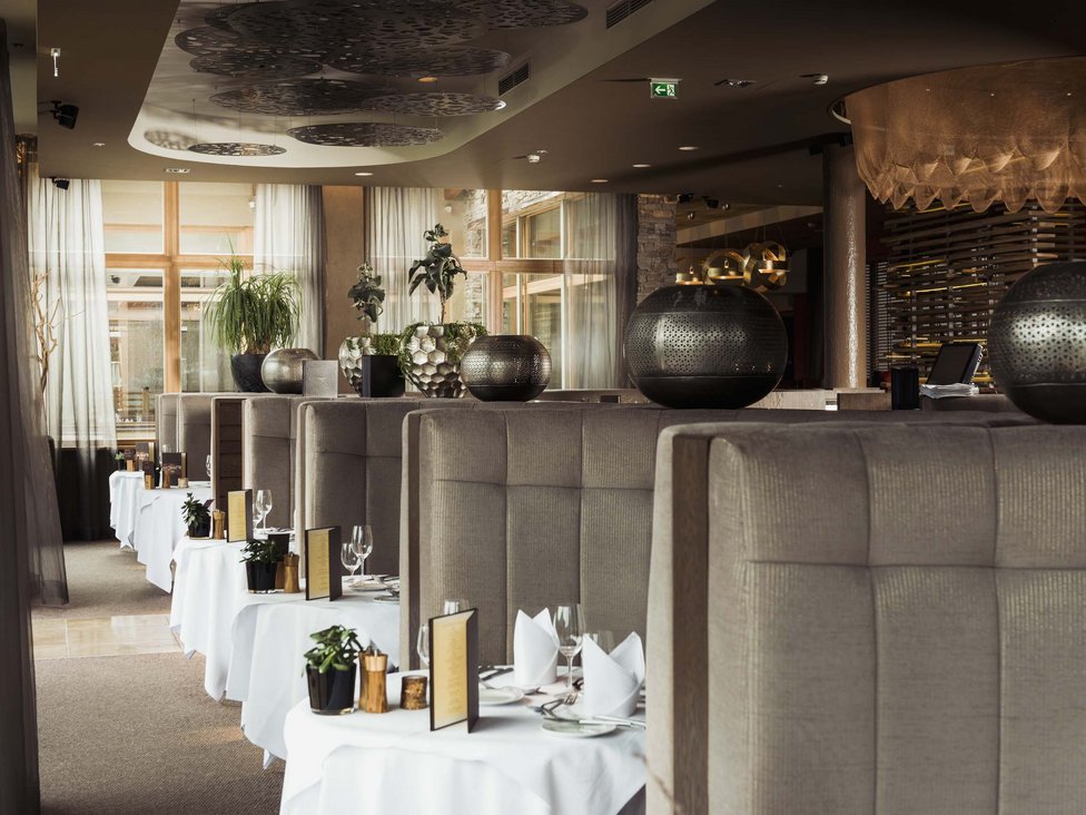Wellness und Luxus: Ihr Hotel in Tirol Elegantes Restaurant mit Tischreihen und gedämpfter Beleuchtung