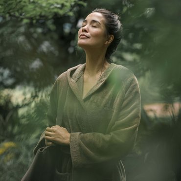 Frau entspannt mit geschlossenen Augen im grünen Garten