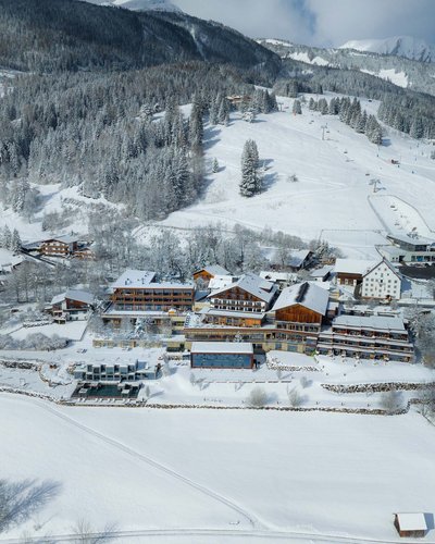 Verschneite Alpenlandschaft mit Skiresort und Bergwald