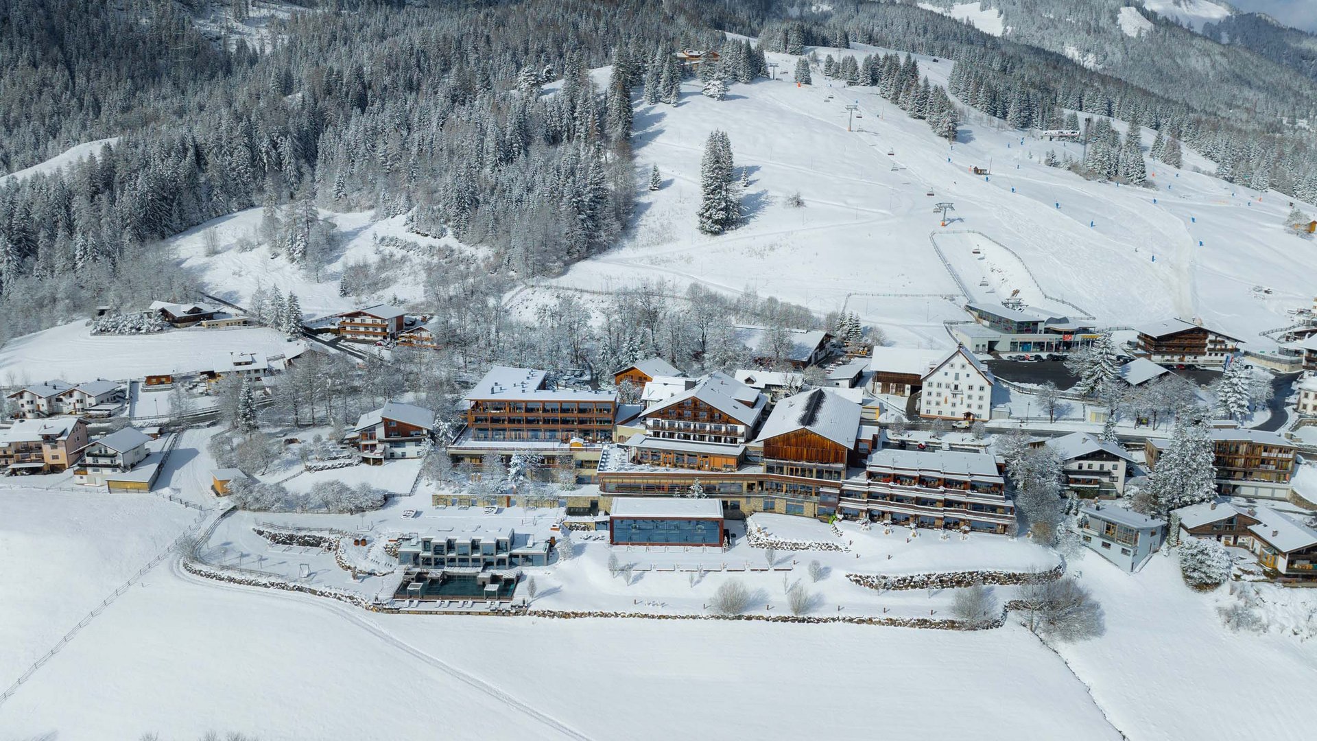 Ein Blick zurück auf die Geschichte des MOHR life resort Verschneite Alpenlandschaft mit Skiresort und Bergwald