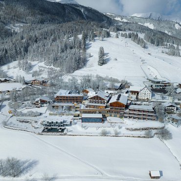 Verschneite Alpenlandschaft mit Skiresort und Bergwald