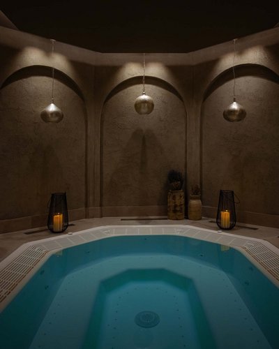 MOHR life resort – wonderful wellness hotel in Lermoos Lit hot tub in a dark round room with candles and hanging lamps