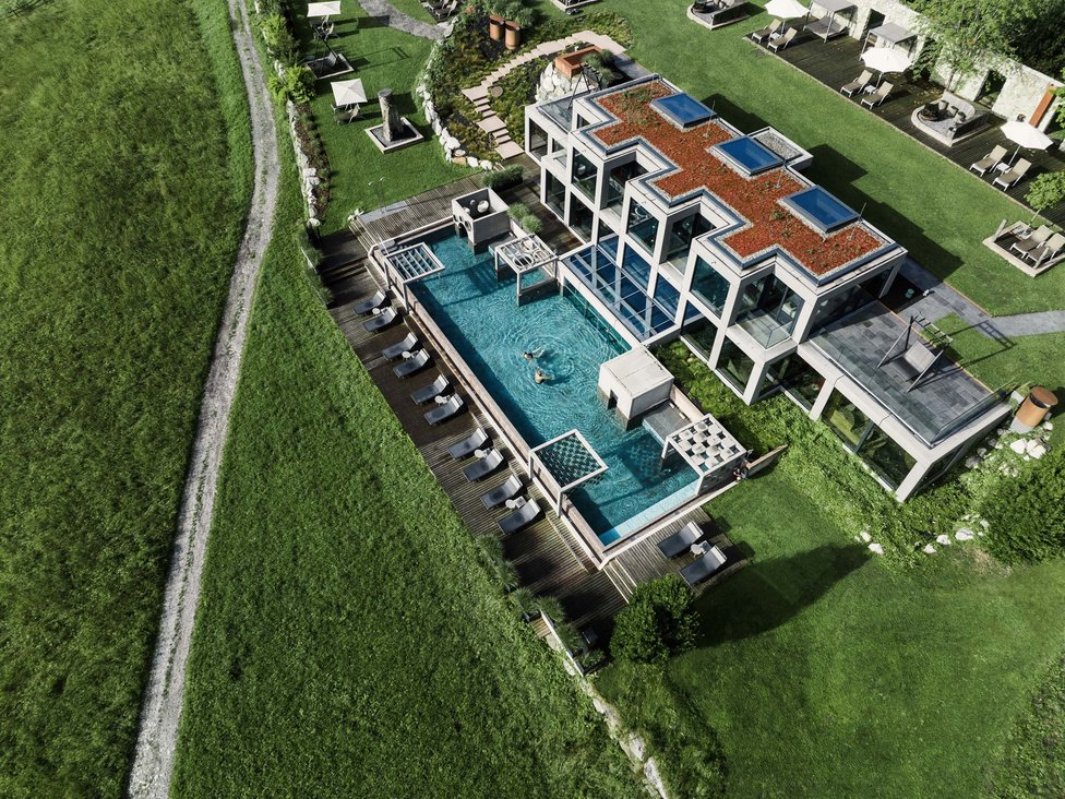 Moderner Wellnessbereich mit Außenpool vor einem Hotel in grüner Landschaft