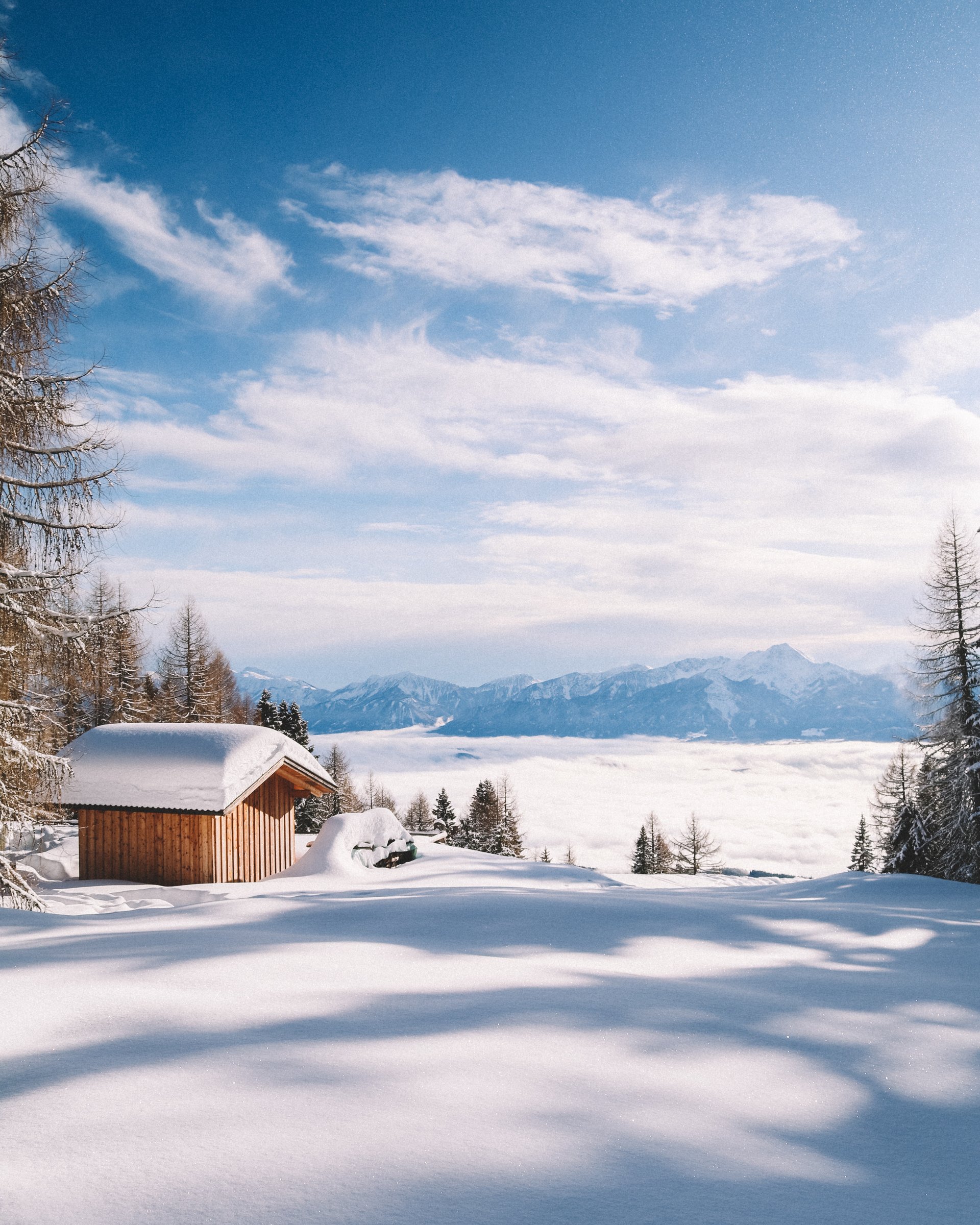 Schneebedecktes Holzhaus in winterlicher Berglandschaft mit blauem Himmel
