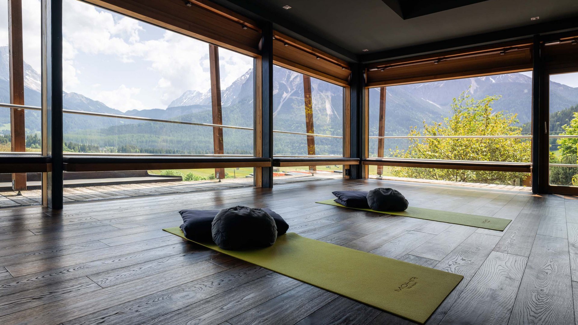 Yoga-Raum mit Blick auf Berge und zwei Matten mit Kissen