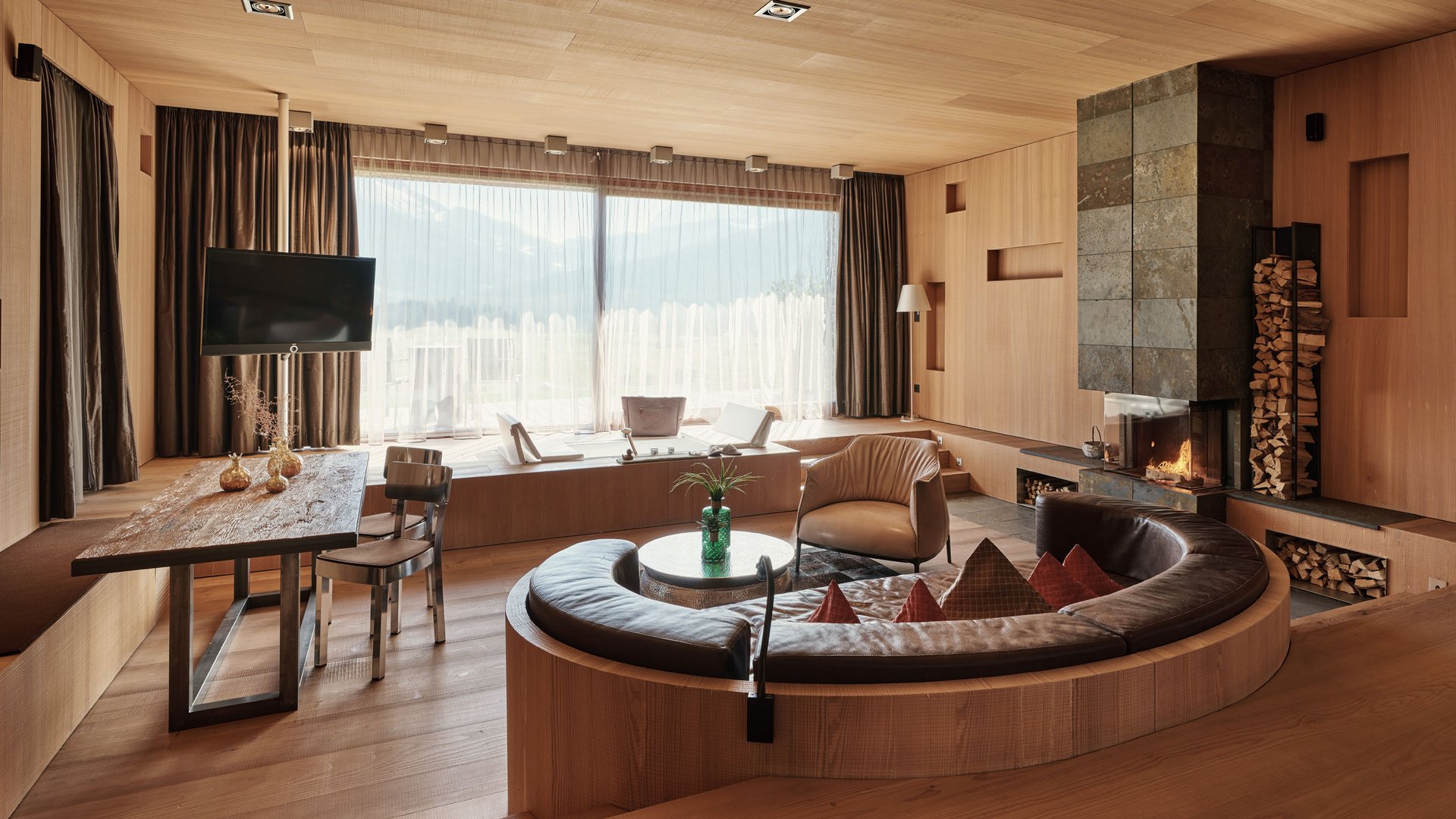 Modernes Wohnzimmer mit großem Fenster, Kamin und rundem Ledersofa