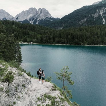 Wanderer auf Felsen mit Blick auf See und Berge im Hintergrund