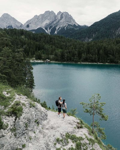 Hikers on rock overlooking lake and mountains in the background