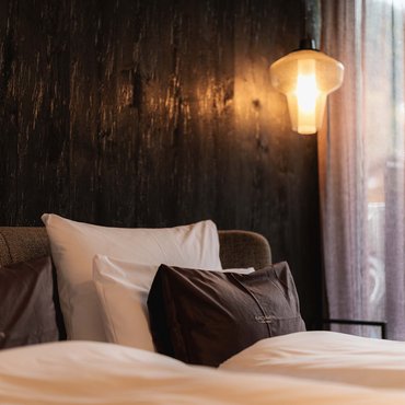 Gemütliches Doppelbett mit braunen und weißen Kissen, warme Beleuchtung