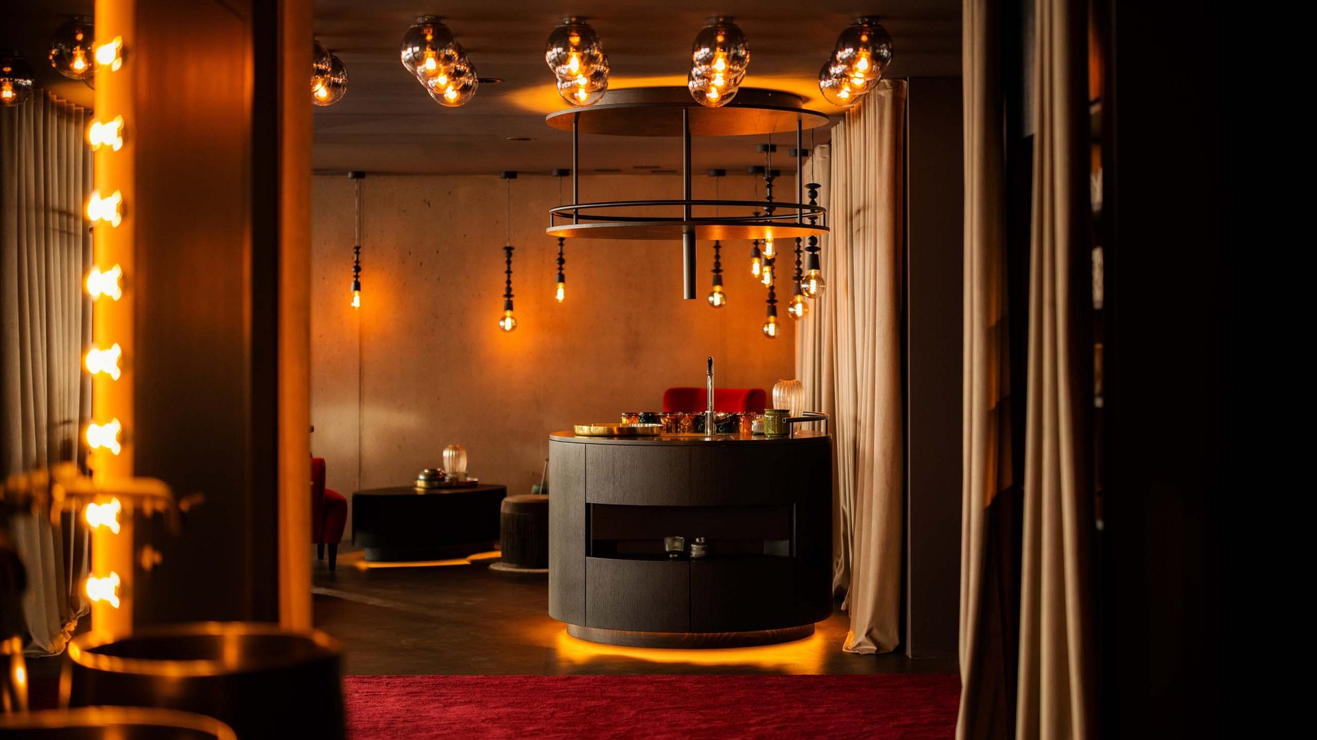 Stilvoll beleuchteter Raum mit runder Bar und rotem Teppich