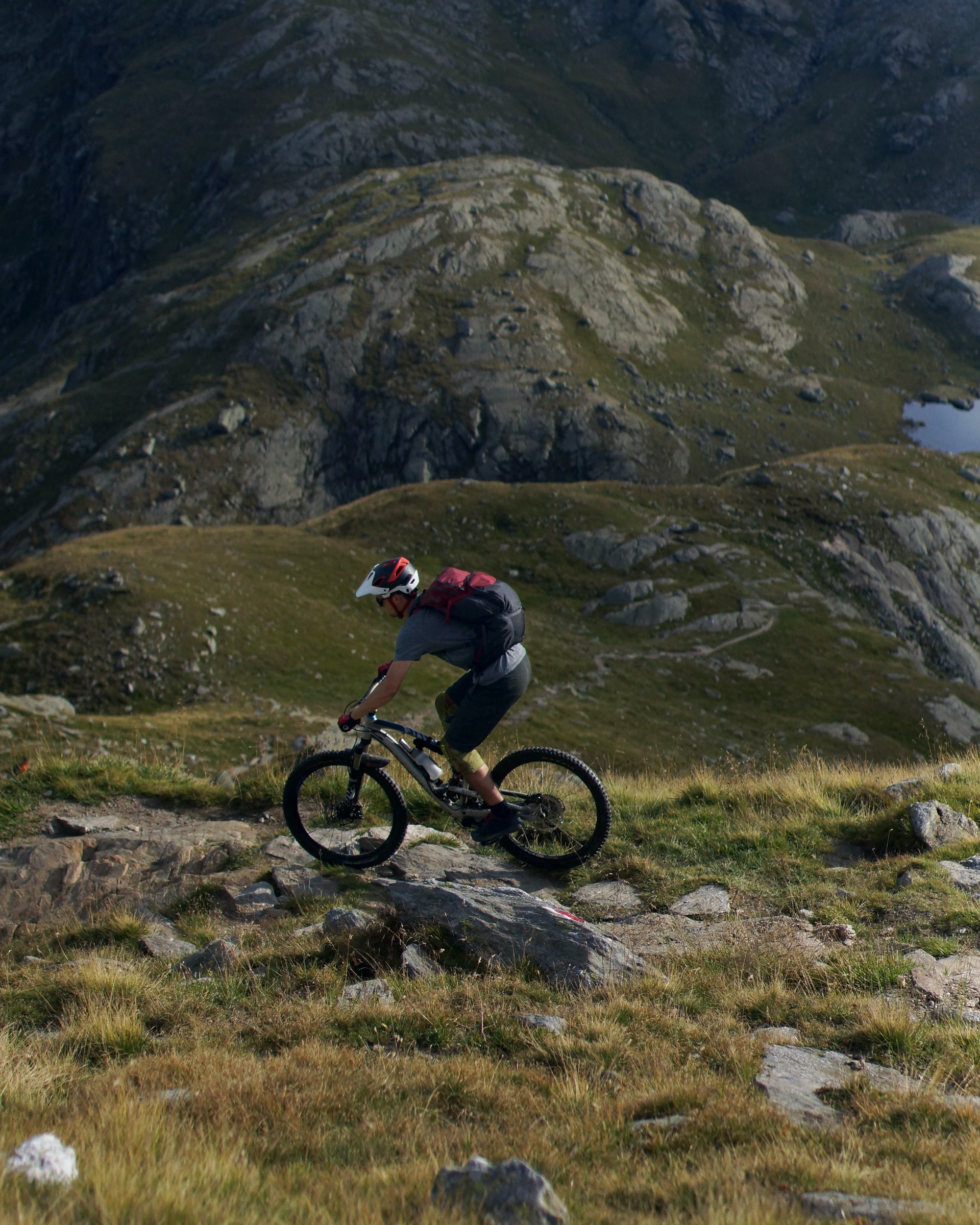 Mountainbiker fährt auf felsigem Pfad im Gebirge bei Sonnenschein