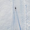 Zwei Personen fahren Skilanglauf im frischen Schnee von oben gesehen