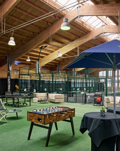 Finally play indoor padel Lermoos in Tyrol – at MOHR life resort Indoor view of two paddle tennis courts with players and seating areas