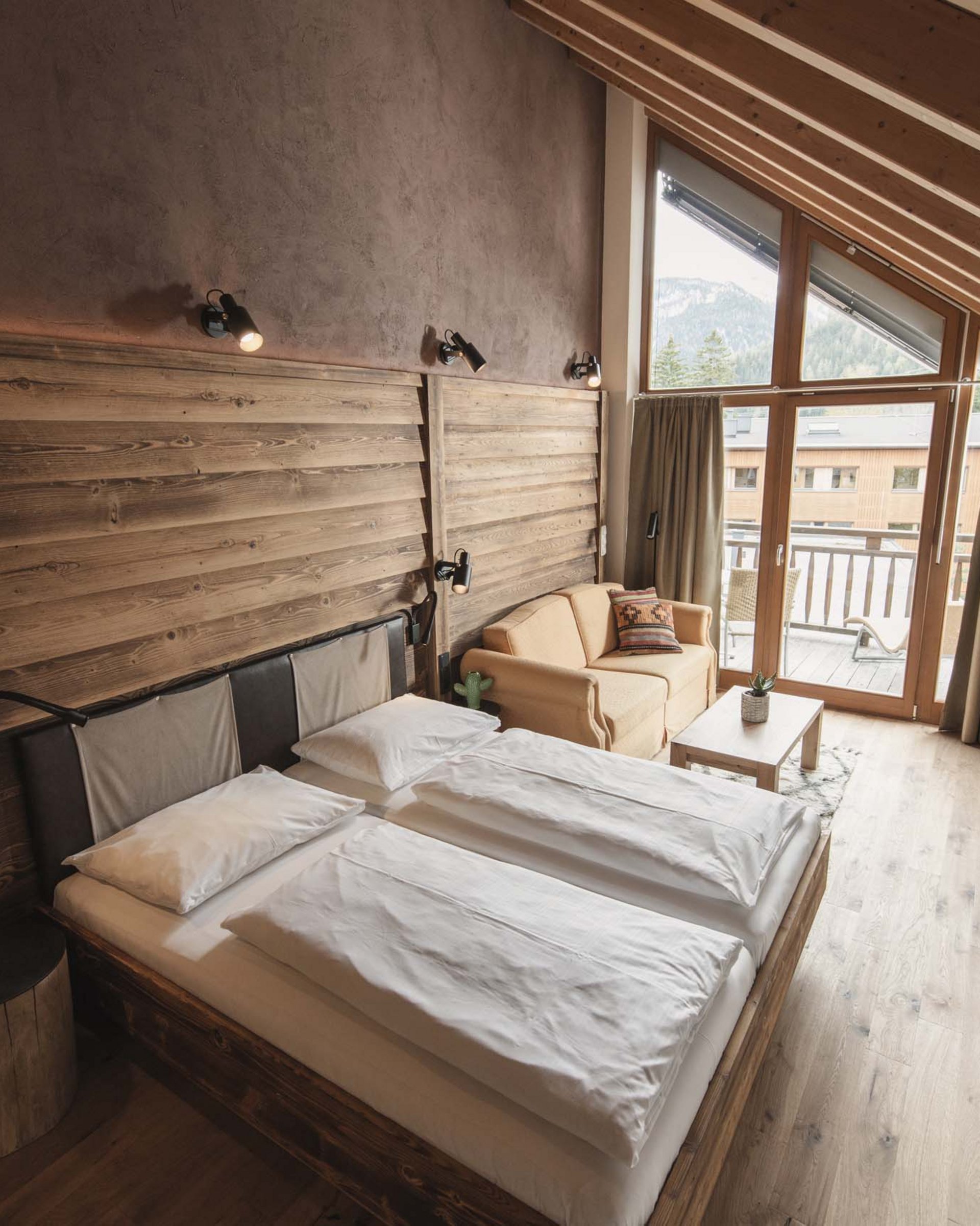 Gemütliches Schlafzimmer mit Doppelbett, Sofa und Balkon in einer Berghütte