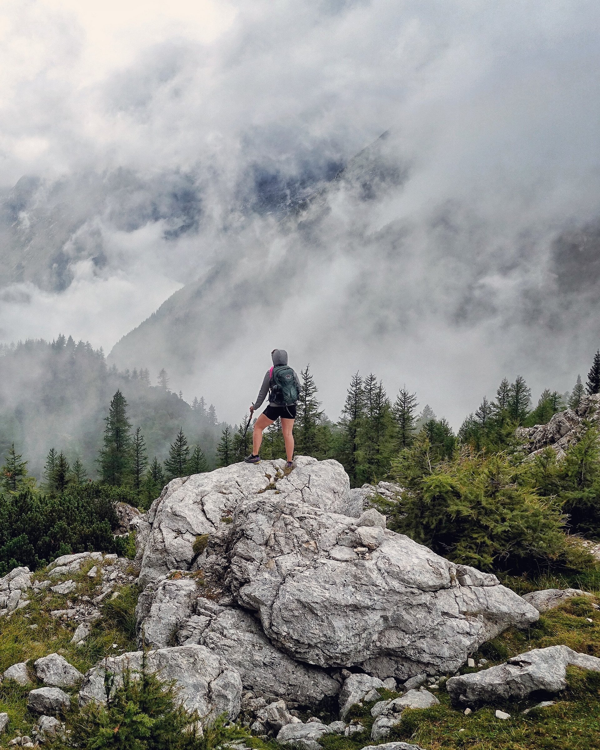 Wanderer steht auf Felsen und blickt auf neblige Berglandschaft