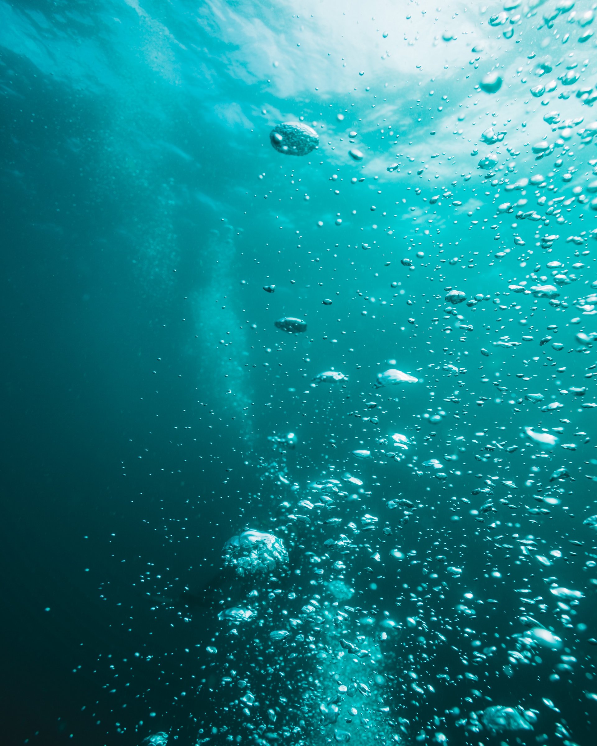 Unterwasseraufnahme mit aufsteigenden Luftblasen im blauen Wasser