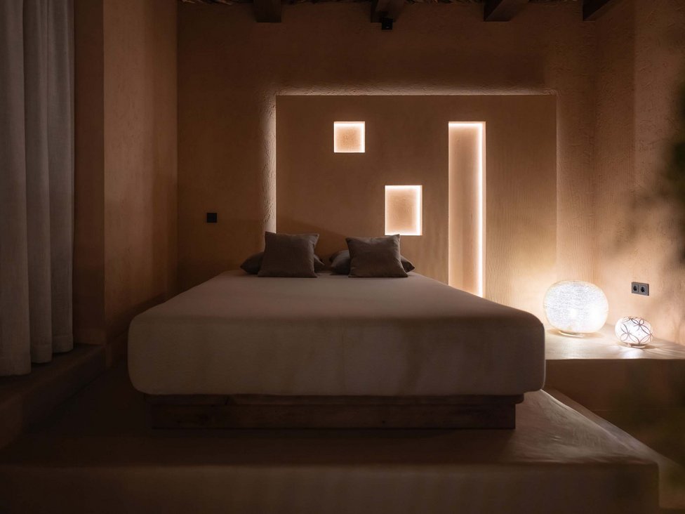 Schlichtes Schlafzimmer mit indirekter Wandbeleuchtung und zwei Lampen