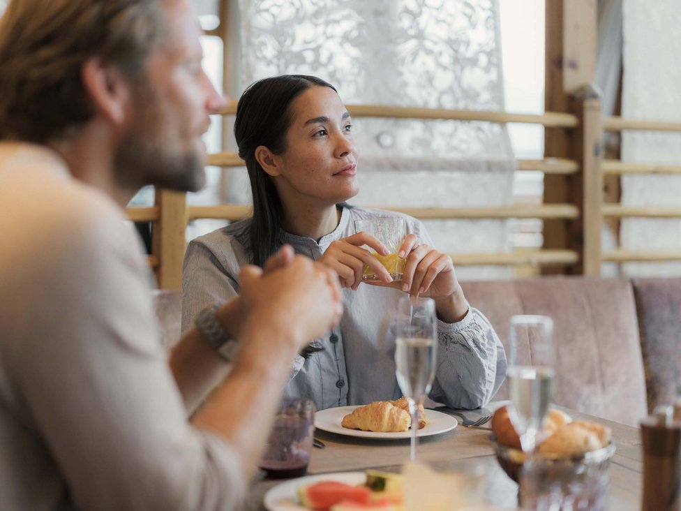 Frau hält Glas beim Frühstücksgespräch mit Mann im Café