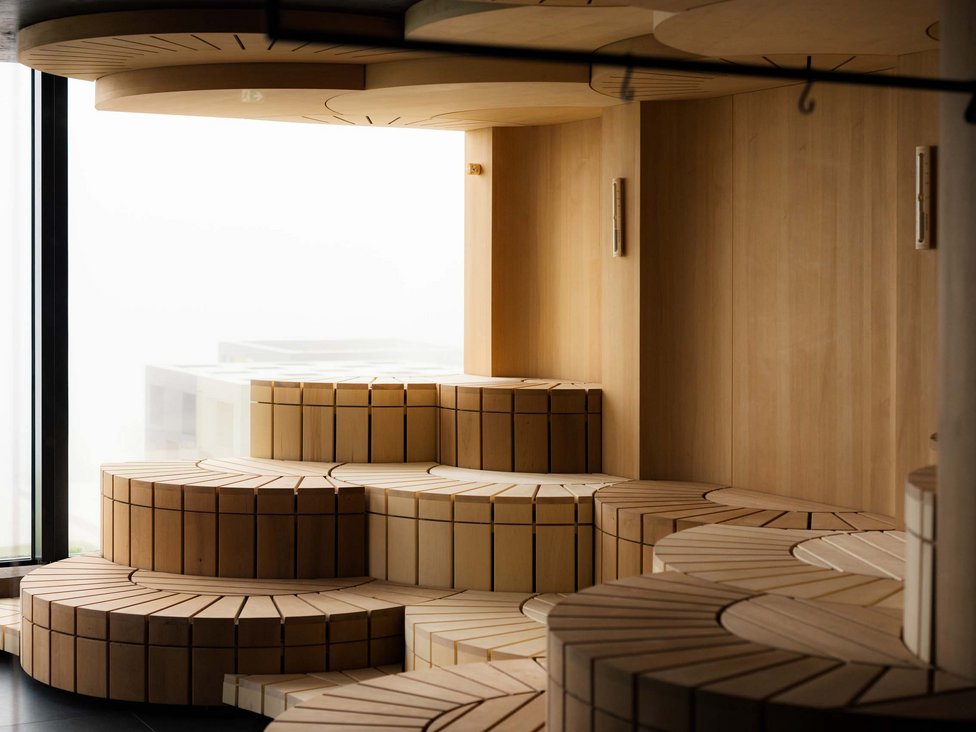 Modernes, gestuftes Holzsofa in hellen natürlichen Tönen vor Fenster