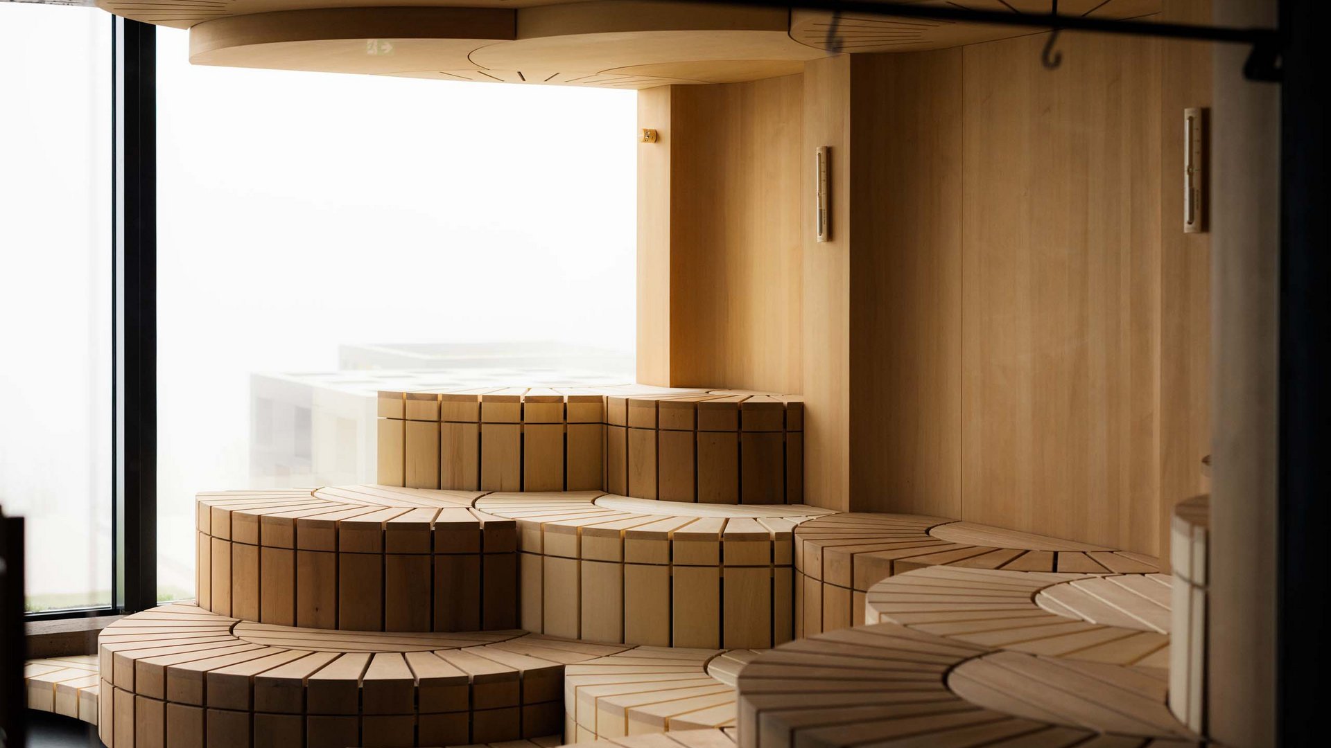 Modernes, gestuftes Holzsofa in hellen natürlichen Tönen vor Fenster