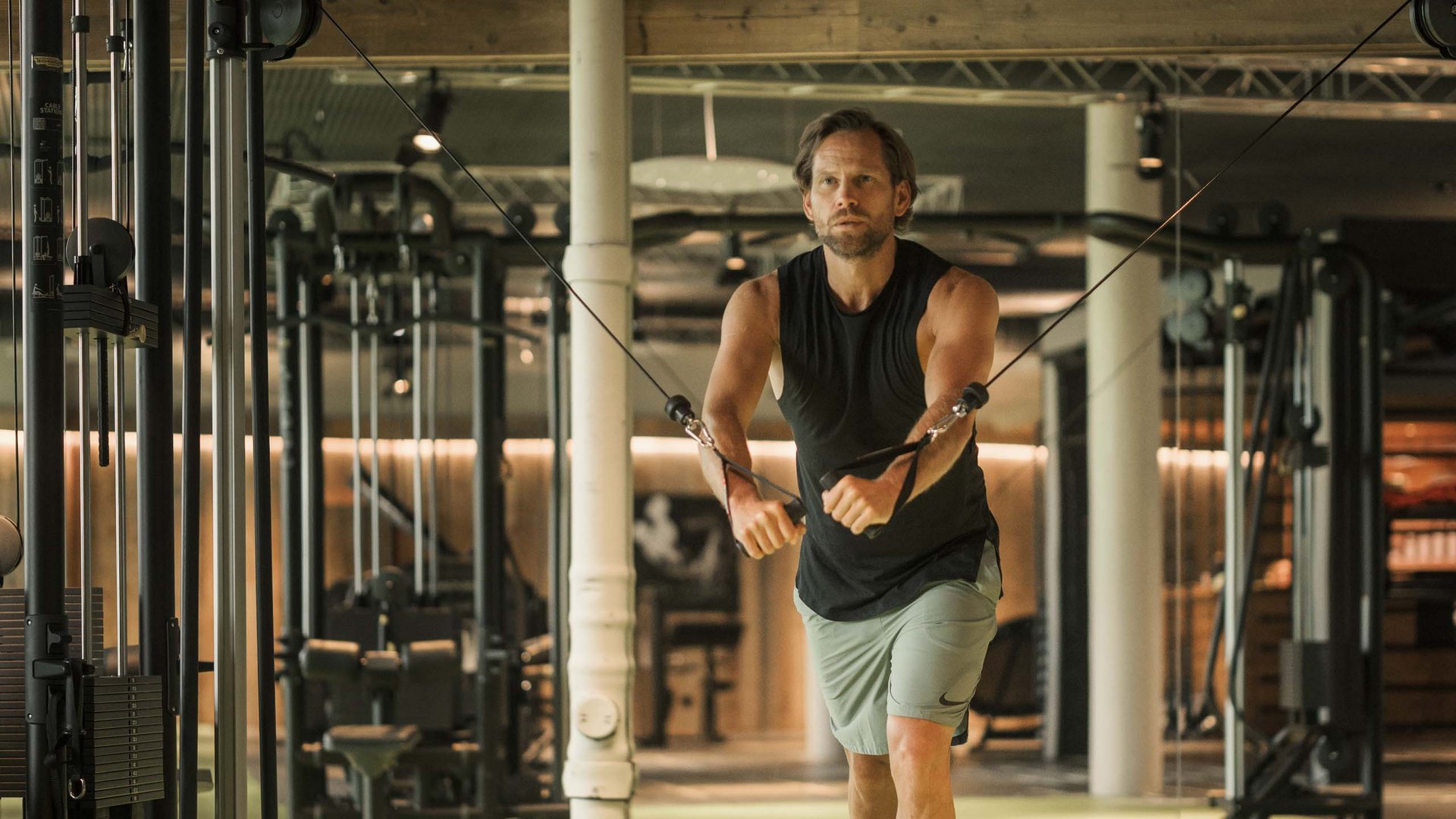 Mann trainiert mit Kabelzug in modernem Fitnessstudio