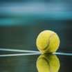 Tennisball auf nassem Tennisplatz mit Reflexion