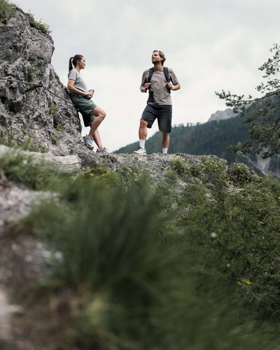 Wellness und Luxus: Ihr Hotel in Tirol Zwei Wanderer machen Pause auf einem felsigen Berg mit bewölktem Himmel