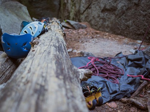 Kletterausrüstung mit Helm, Seil und Schuhen an einem Felsen