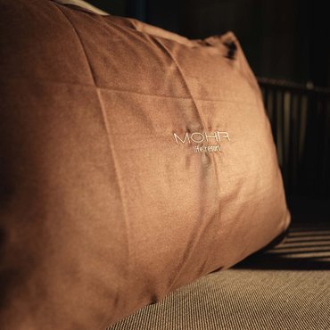 Braunes Kissen mit MOHR life resort Schriftzug im Sonnenlicht