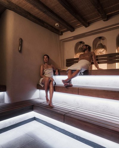 Zwei Personen entspannen in einem beleuchteten Holzsaunainterieur