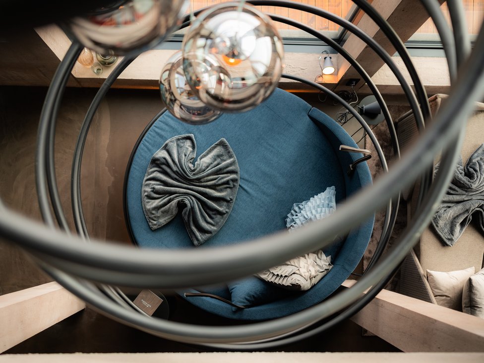 Blick von oben auf einen blauen runden Sessel mit Kissen und moderne Lampen